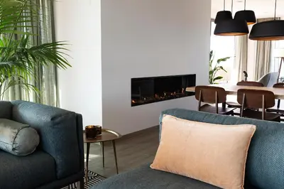 a living room with a couch and a fireplace at Droomsuites Egmond aan Zee 8 personen by Droomvilla in Egmond aan Zee