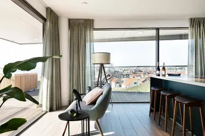 a living room with a couch and a large window at Droomsuites Egmond aan Zee 8 personen by Droomvilla in Egmond aan Zee