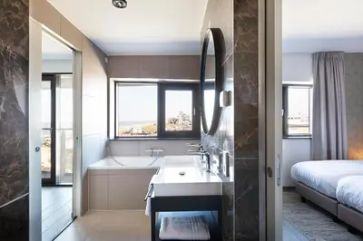 a bathroom with a tub and a sink and a bed at Droomsuites Egmond aan Zee 8 personen by Droomvilla in Egmond aan Zee