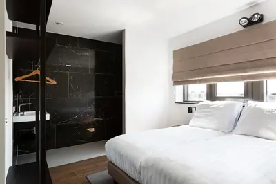 a bedroom with a white bed and a black wall at Droomsuites Egmond aan Zee 8 personen by Droomvilla in Egmond aan Zee