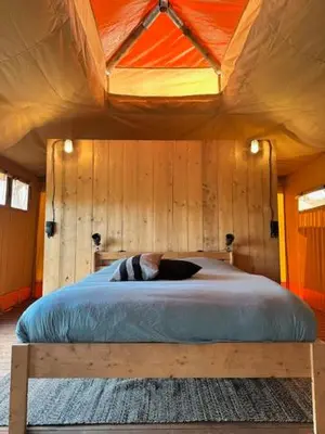 a bedroom with a large bed with a wooden ceiling at Safari Lodge at Back to Basic in Zwaanshoek