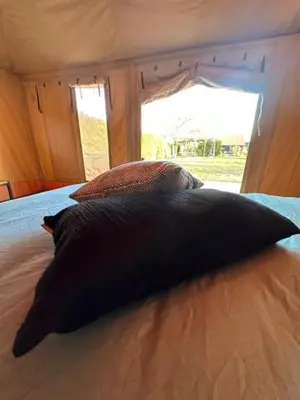 a large black pillow on a bed with a window at Safari Lodge at Back to Basic in Zwaanshoek