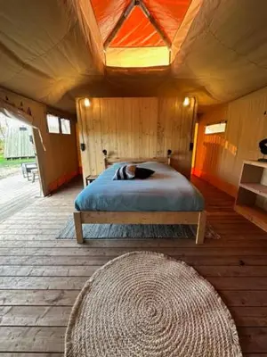 a bedroom with a bed in a wooden house at Safari Lodge at Back to Basic in Zwaanshoek