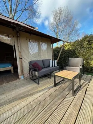a wooden deck with a couch and a table at Safari Lodge at Back to Basic in Zwaanshoek