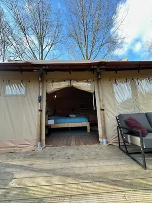 a tent with a bed and a chair in it at Safari Lodge at Back to Basic in Zwaanshoek