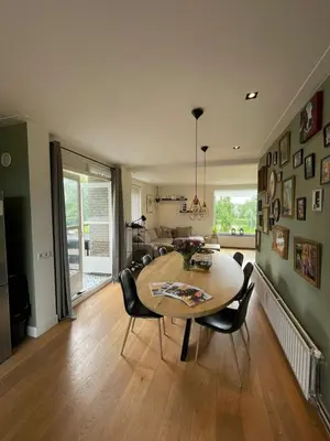 a living room with a dining room table and chairs at Prachtige, lichte condo met balkon in Bergen