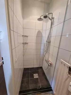 a shower with a glass door in a bathroom at Prachtige, lichte condo met balkon in Bergen