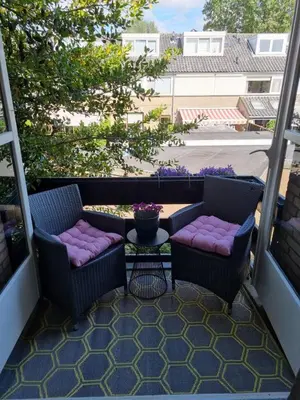 a patio with two chairs and a table on a balcony at Prachtige, lichte condo met balkon in Bergen