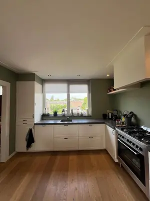 a kitchen with white cabinets and a sink and a window at Prachtige, lichte condo met balkon in Bergen
