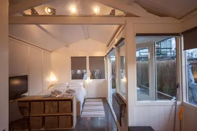 a small room with a bed and a table and a tv at Tiny House Madame Jeanette nabij centrum en zee in Zandvoort