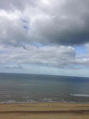 a beach with a cloudy sky and the ocean at Tiny House Madame Jeanette nabij centrum en zee in Zandvoort