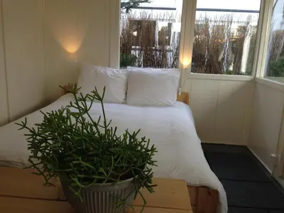 a bedroom with a white bed and a potted plant at Tiny House Madame Jeanette nabij centrum en zee in Zandvoort