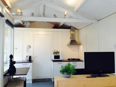 a kitchen with a tv on a wooden table at Tiny House Madame Jeanette nabij centrum en zee in Zandvoort