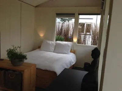 a small bedroom with a bed and a window at Tiny House Madame Jeanette nabij centrum en zee in Zandvoort
