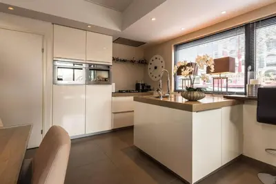a kitchen with white cabinets and a large window at Executive Houseboat-Apartment Sumatra in Amsterdam
