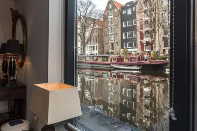 a window with a view of a canal with boats at Executive Houseboat-Apartment Sumatra in Amsterdam