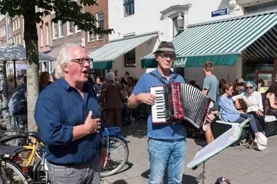 an older man playing an accordion on a street at Executive Houseboat-Apartment Sumatra in Amsterdam