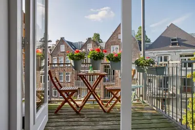 a balcony with two chairs and a table with flowers on it at Charming Apartment in City Centre in Amsterdam