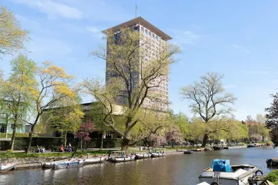 a tall building next to a river with boats in it at Charming Apartment in City Centre in Amsterdam