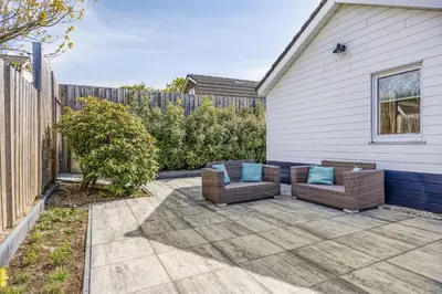 a patio with two chairs and a fence at Cosy Nest in Noordwijk aan Zee