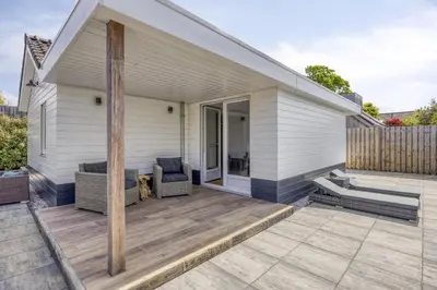 a house with a deck with a chair on it at Cosy Nest in Noordwijk aan Zee