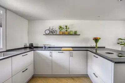 a kitchen with white cabinets and black counter tops at Cosy Nest in Noordwijk aan Zee