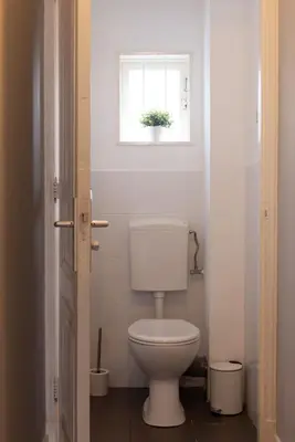 a white toilet in a bathroom with a window at Elegant City Apartment in the Heart of Gouda in Gouda