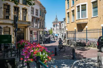 a person riding a bike down a street with flowers at Elegant City Apartment in the Heart of Gouda in Gouda