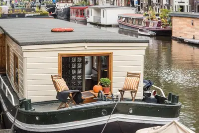 a small house on a boat in a canal at Luxury Houseboat Prince-William in Amsterdam