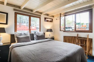 a bedroom with a bed and two windows at Luxury Houseboat Prince-William in Amsterdam