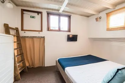 a small bedroom with a bed and a ladder at Luxury large Houseboat AZARA in Amsterdam