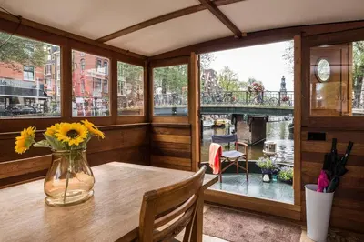 a room with a table with a vase of flowers on it at Luxury large Houseboat AZARA in Amsterdam