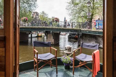two chairs sitting on a balcony overlooking a canal at Luxury large Houseboat AZARA in Amsterdam