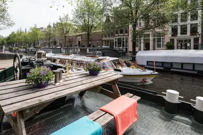 a wooden table with flowers and a boat on a canal at Luxury large Houseboat AZARA in Amsterdam