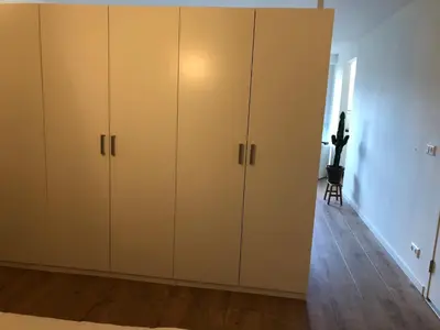 a bedroom with white cabinets and a wooden floor at Savina oase nabij centrum, zee en station in Zandvoort