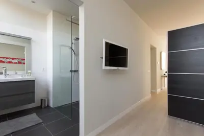 a bathroom with a shower and a television on a wall at Savina oase nabij centrum, zee en station in Zandvoort