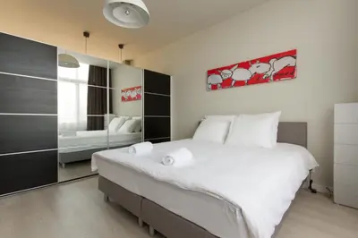 a bedroom with a large white bed and a mirror at Savina oase nabij centrum, zee en station in Zandvoort