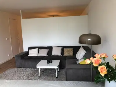 a living room with a black couch and a table at Savina oase nabij centrum, zee en station in Zandvoort