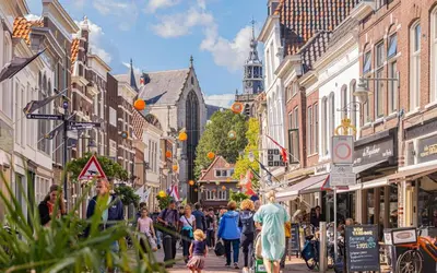 a crowd of people walking down a city street at Characteristic Dutch home in historic center Gouda in Gouda