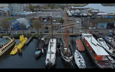 a group of boats are docked in a harbor at The Vega 1909 - Historic Wooden Ship in Amsterdam