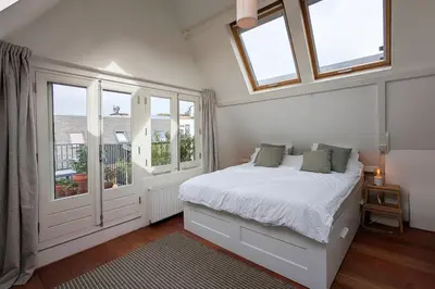 a white bedroom with a bed and windows at Charming Apartment with Roof Terrace in Amsterdam