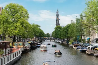a group of boats in a canal with a clock tower at Charming Apartment with Roof Terrace in Amsterdam