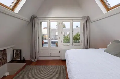 a white bedroom with a bed and a window at Charming Apartment with Roof Terrace in Amsterdam