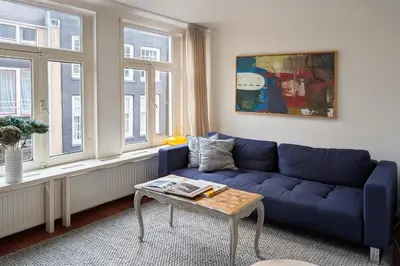 a blue couch in a living room with windows at Charming Apartment with Roof Terrace in Amsterdam