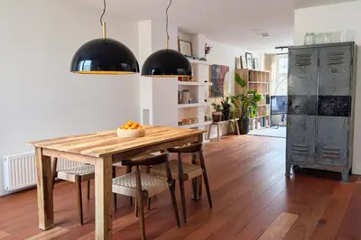 a kitchen with a wooden table and black pendant lights at Charming Apartment with Roof Terrace in Amsterdam