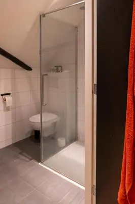 a glass shower in a bathroom with a toilet at Op Vakantie bij Nicole in Putten