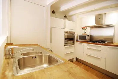 a kitchen with a stainless steel sink and white cabinets at Canal view luxury apartment in the Jordaan in Amsterdam