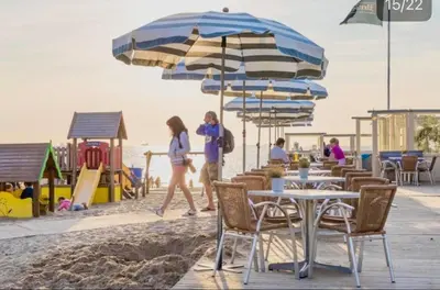 two women walking on the beach with tables and umbrellas at Lovely Apartment Wassenaar 6P in Wassenaar