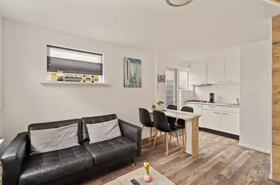 a living room with a black leather couch and a table at Have e nice stay! - Juul 18, free parking in Noordwijk