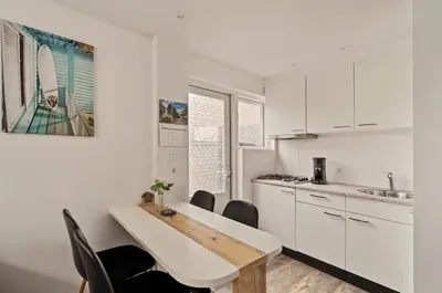 a kitchen with white cabinets and a table and chairs at Have e nice stay! - Juul 18, free parking in Noordwijk